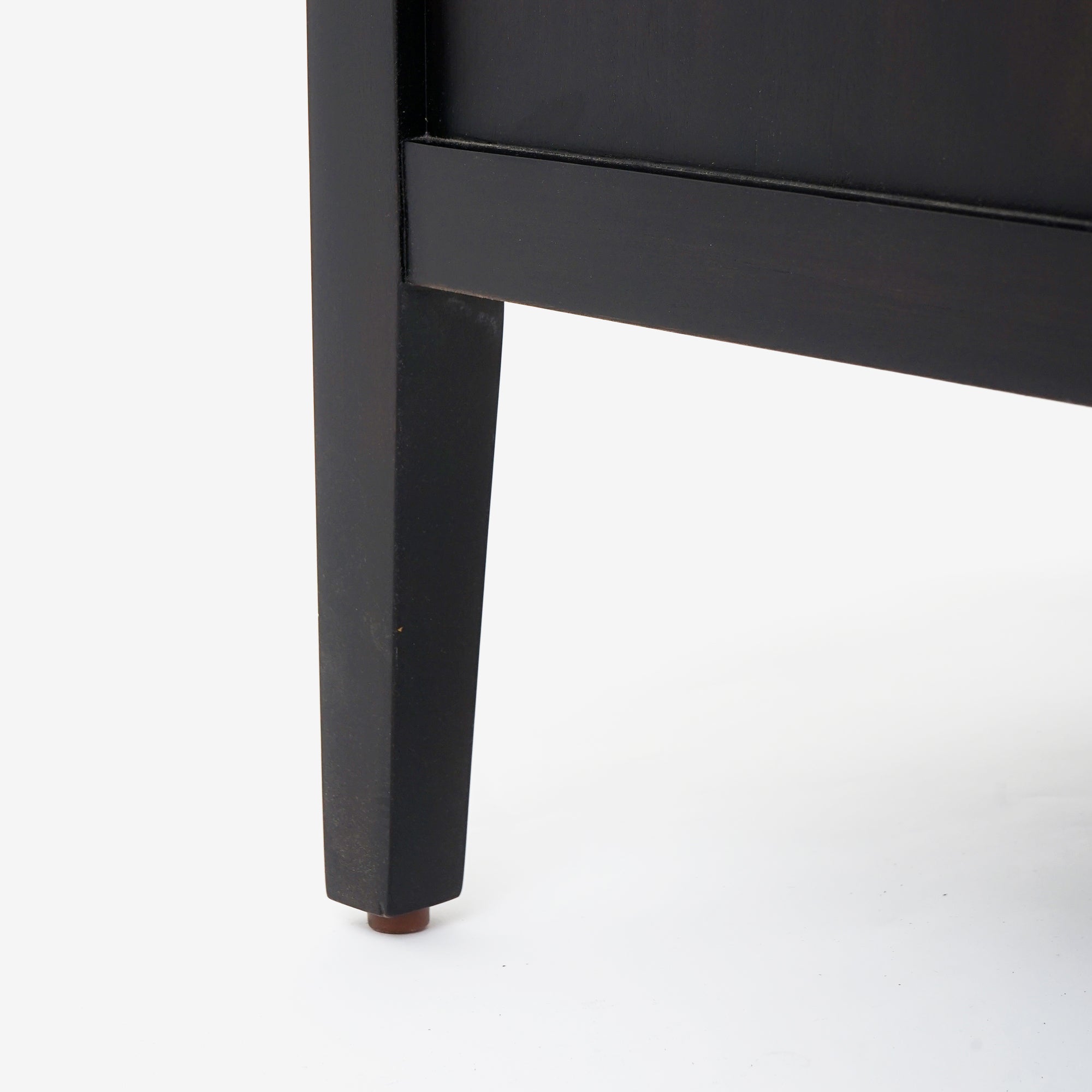 Black wooden leg of a piece of Black Kalana - 2-Drawer Rattan Nightstand