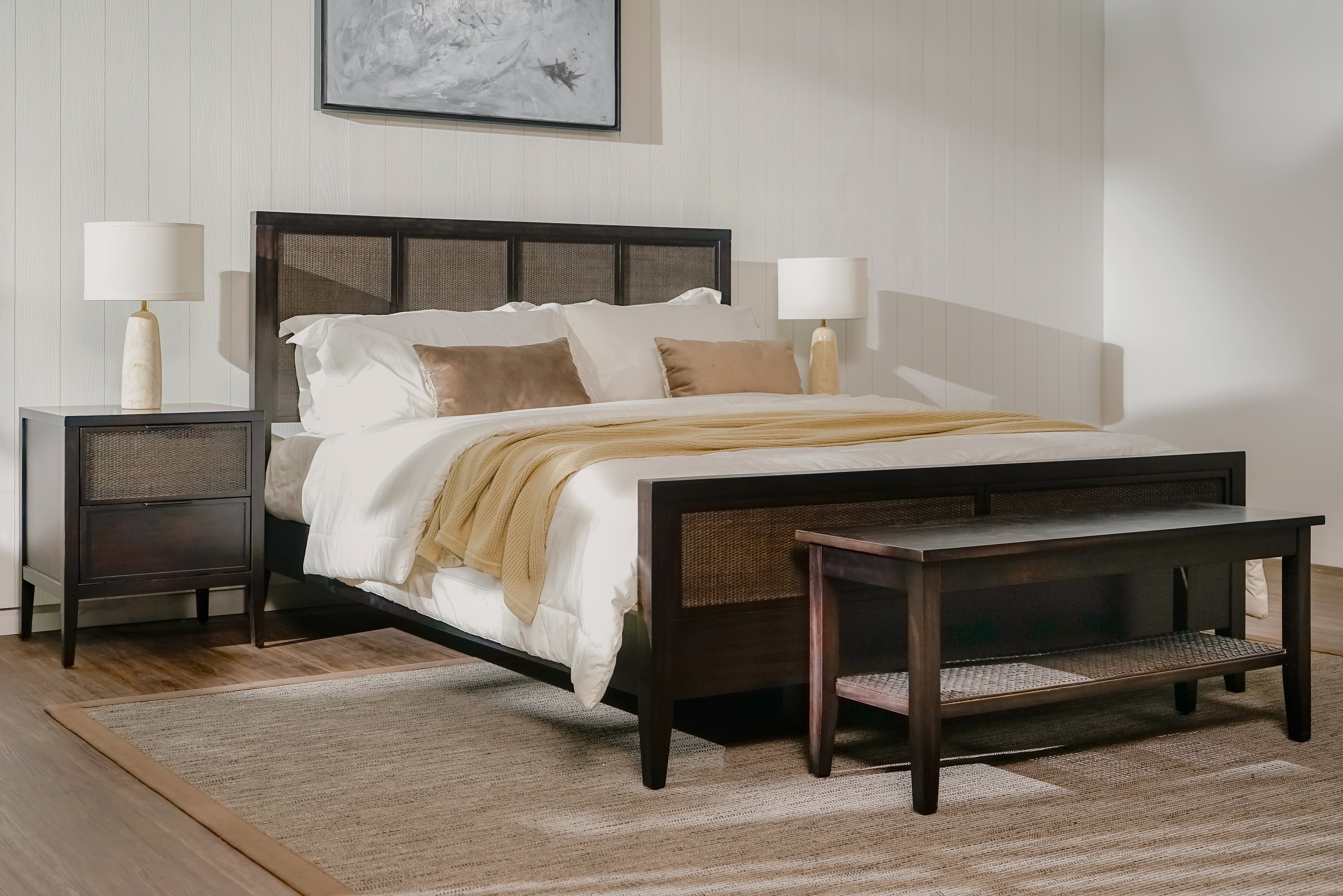 Bedroom with wooden bed, nightstands, and bench in a well-lit room.