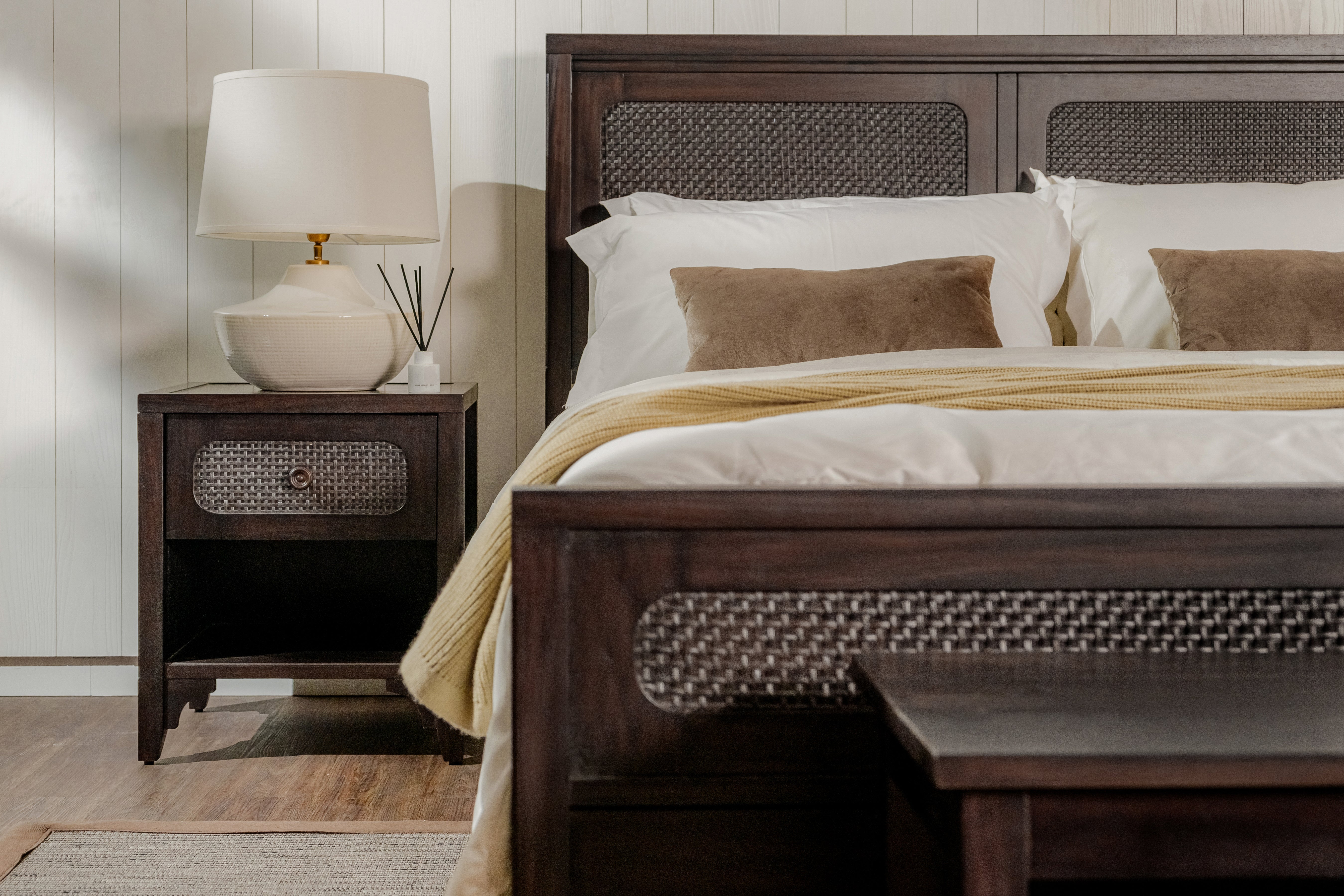 Wooden bed with wicker headboard and nightstand in a bedroom setting