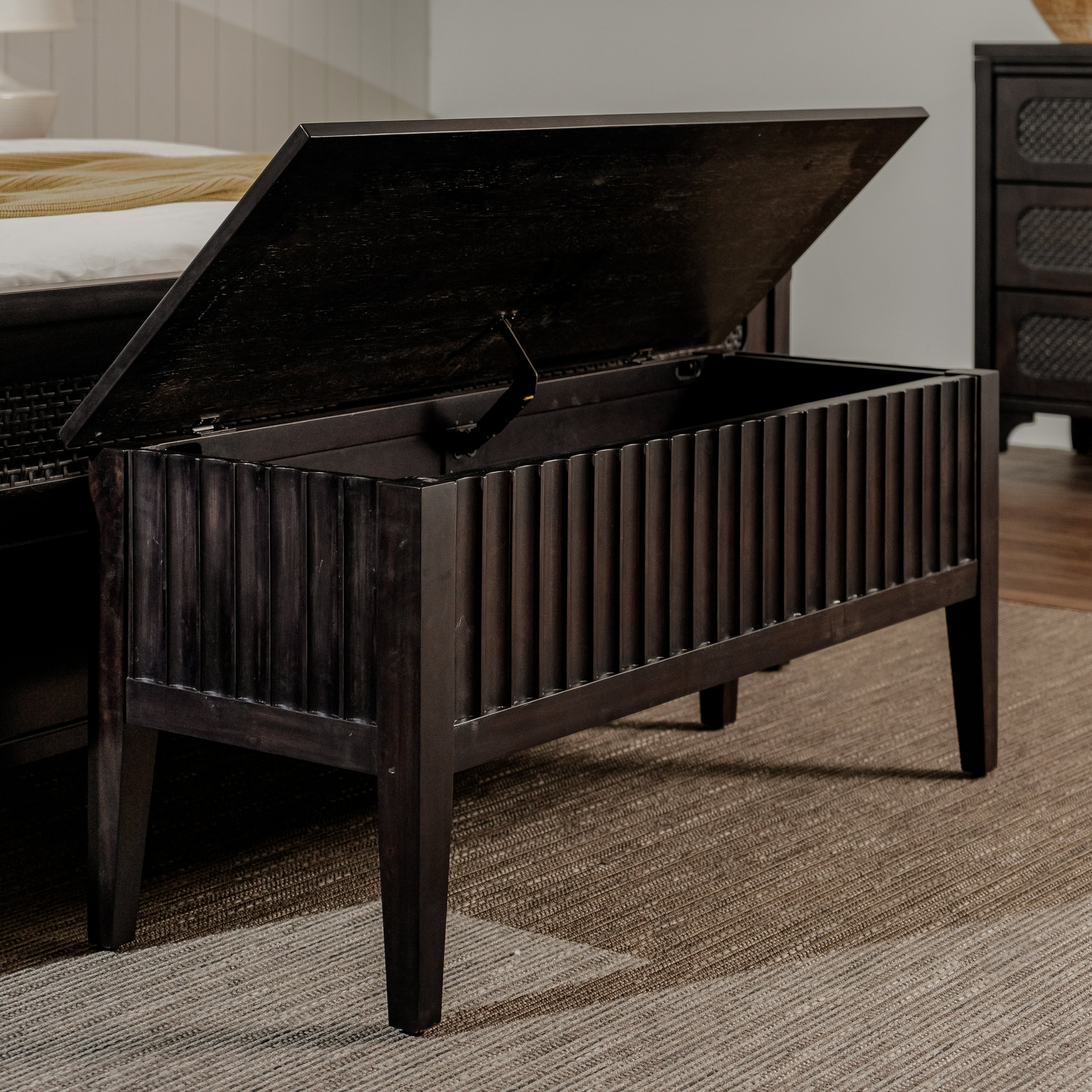 Dark wooden storage bench with open lid in a bedroom setting