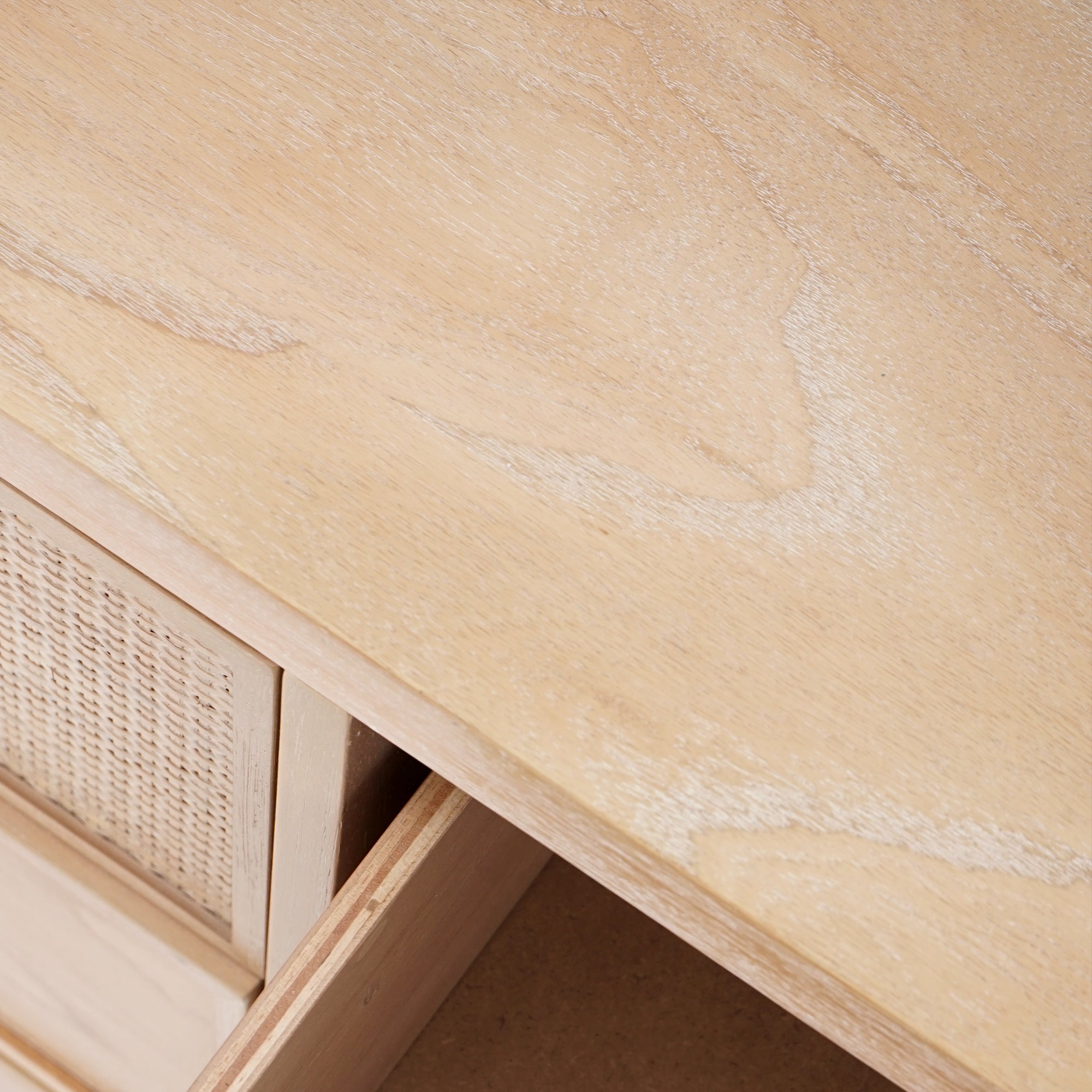 Close-up of a wooden desk with a wicker drawer.