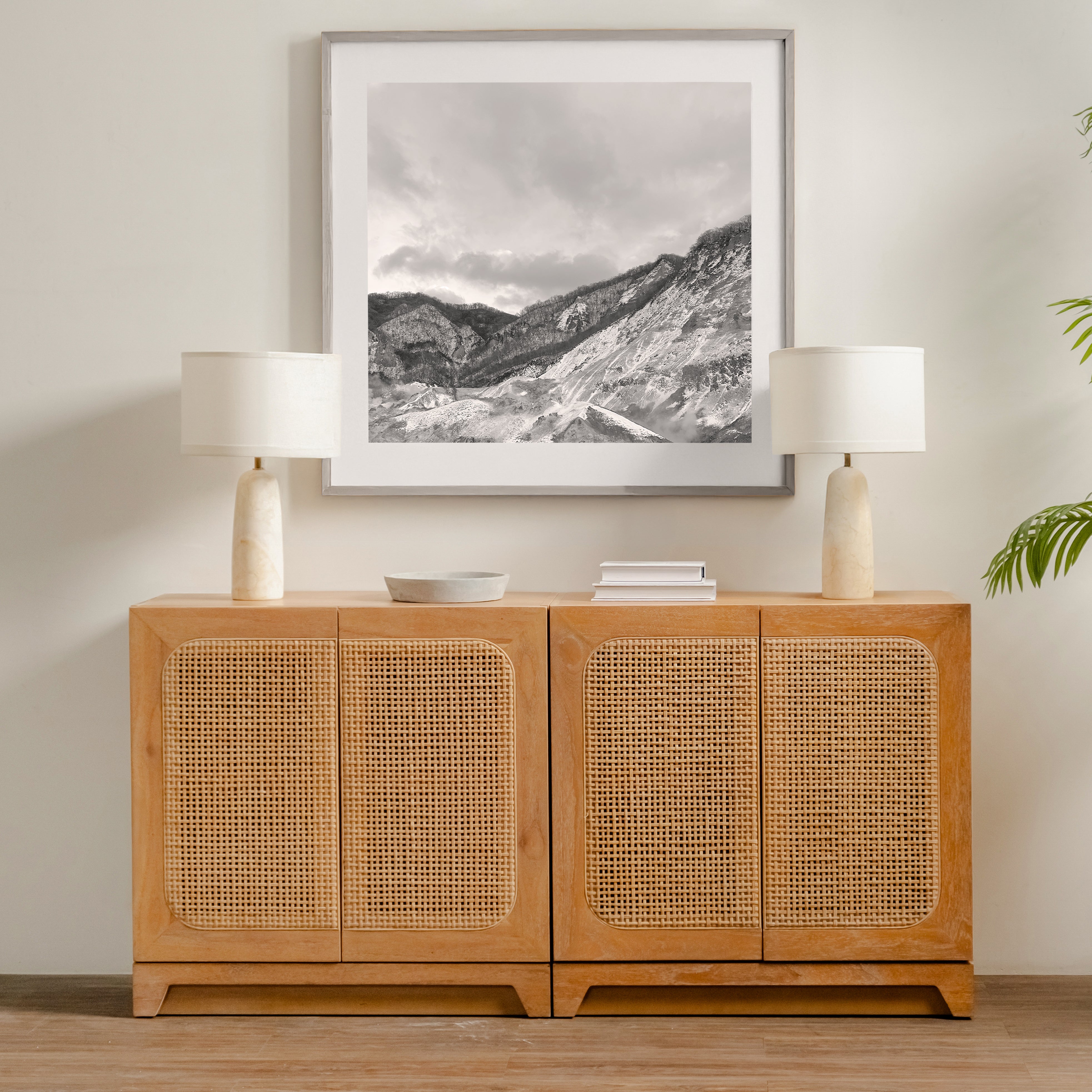 Wooden cabinet with wicker doors in a room with lamps and a framed picture on the wall.