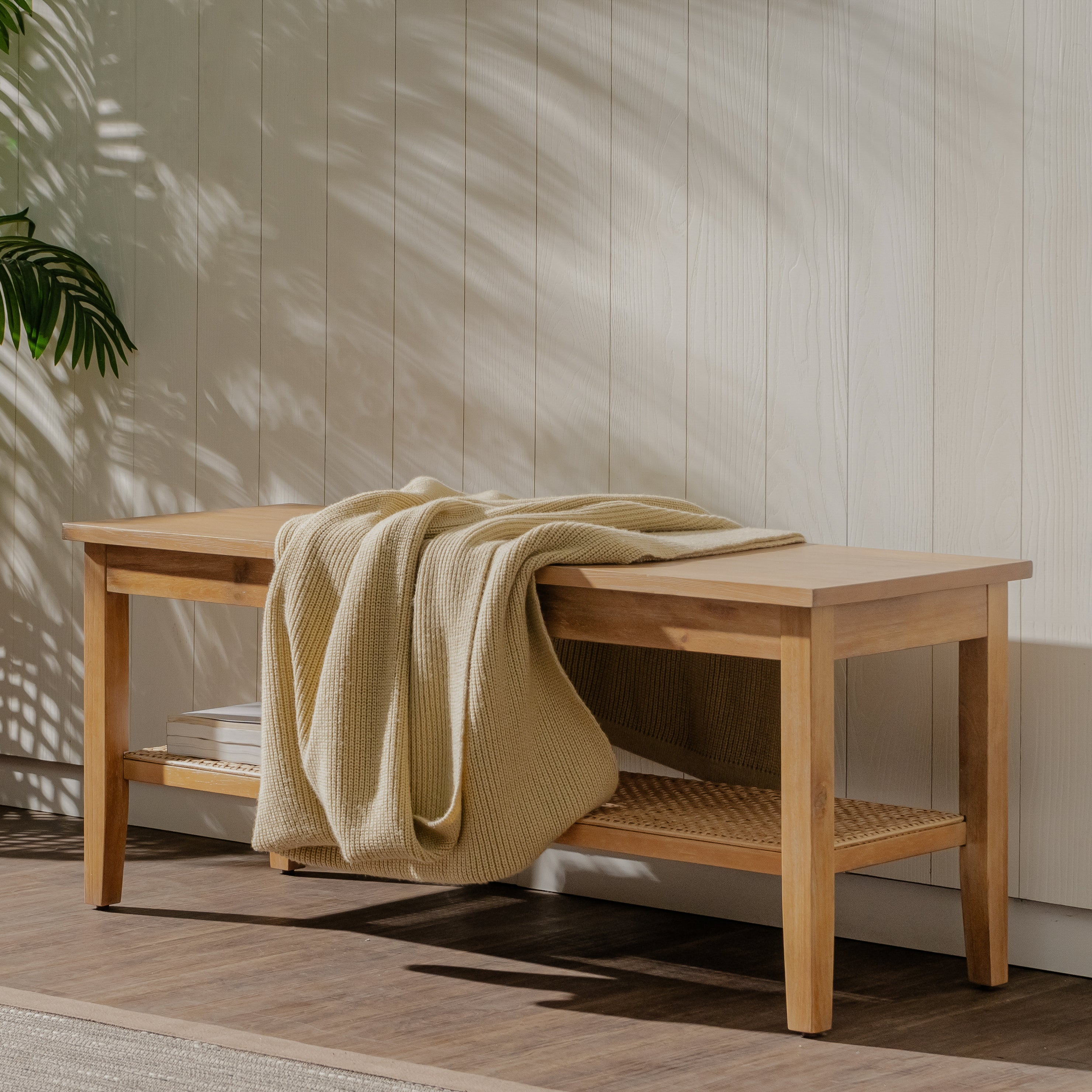 Wooden bench with a yellow blanket draped over it against a neutral wall.