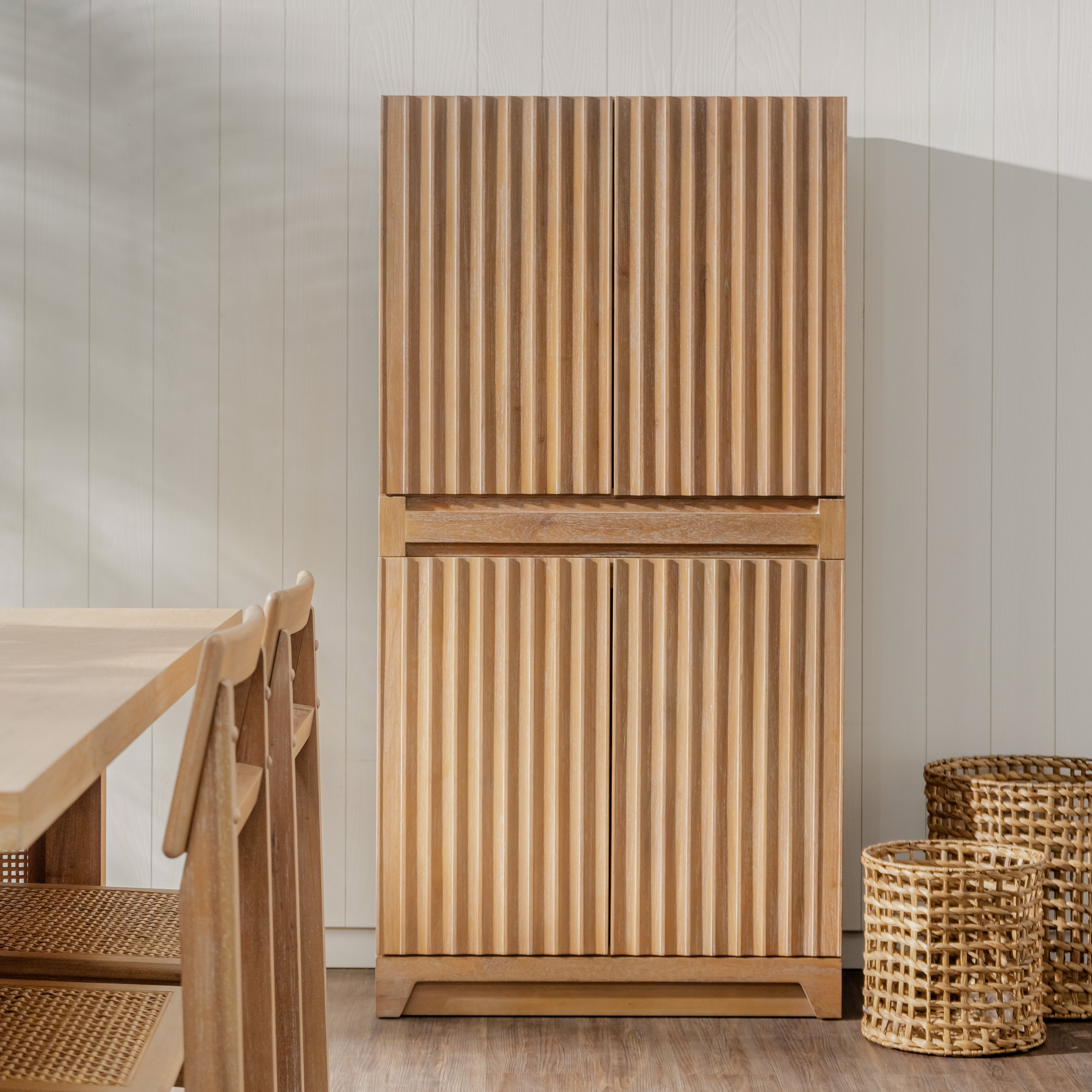 Wooden cabinet with wicker baskets on a wooden floor against a light-colored wall.