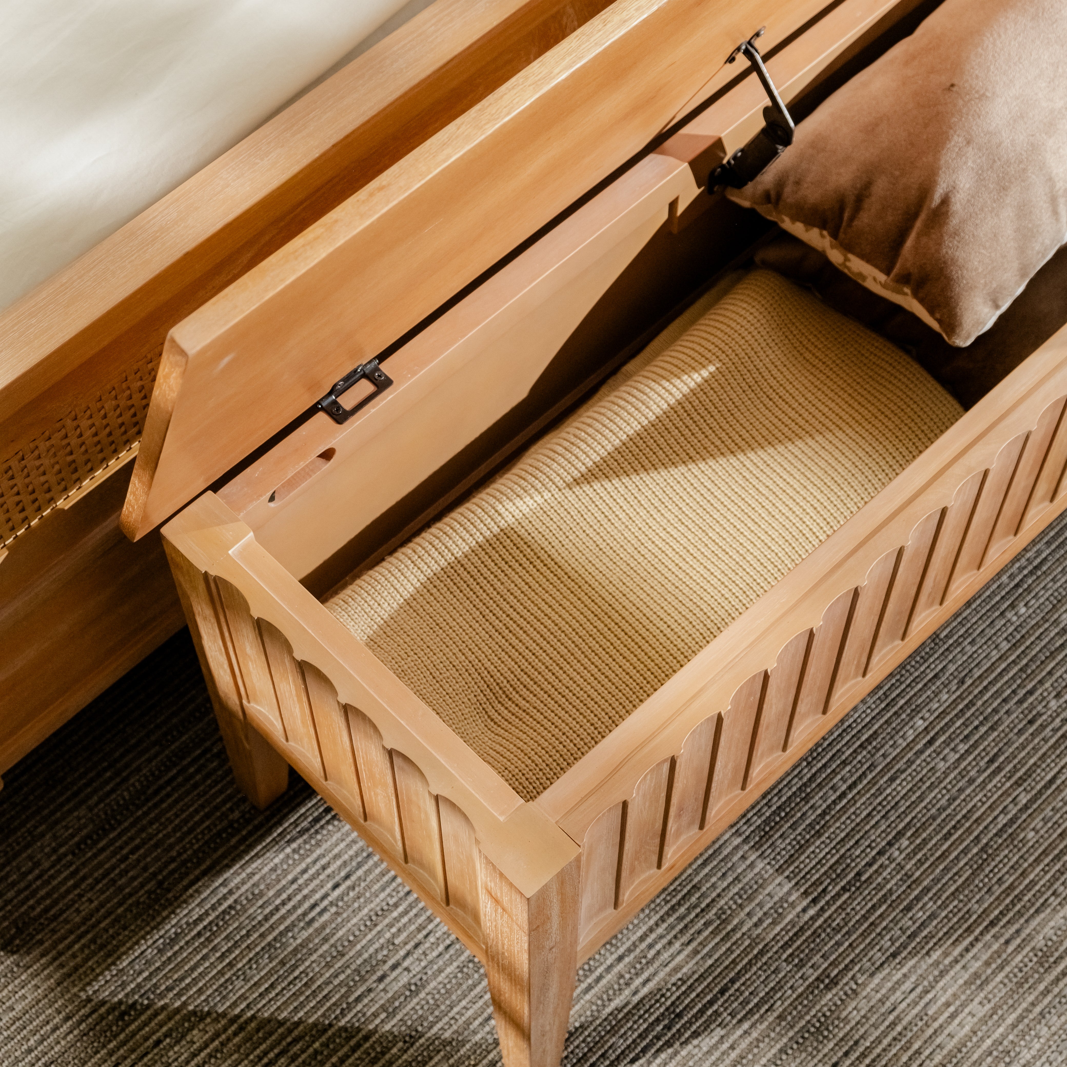 Wooden storage bench with a cushioned seat in a room setting.