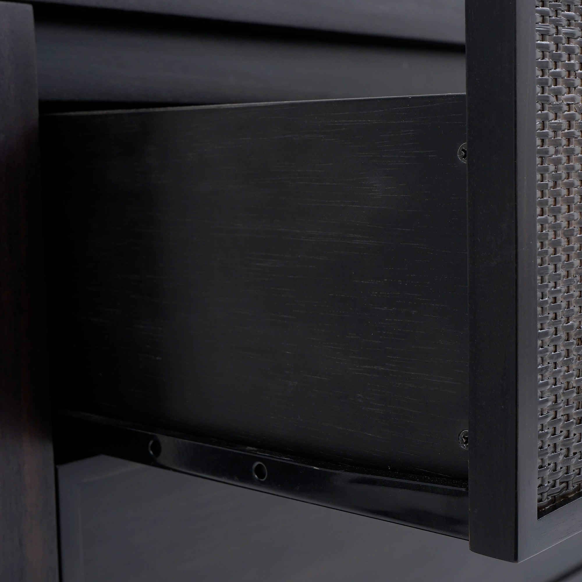 Close-up of a chair with woven backrest and dark wooden frame.