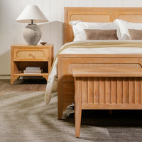 Wooden bed with wicker headboard and nightstand in a bedroom setting.